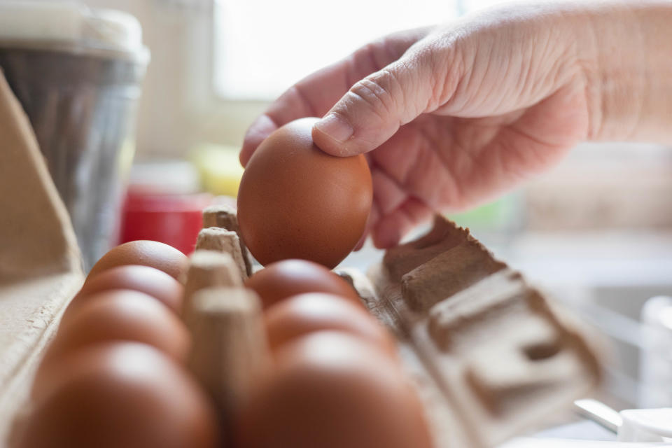 Box of brown eggs in hand on white background isolation, to illustrate story on Singapore importing eggs from Indonesia.