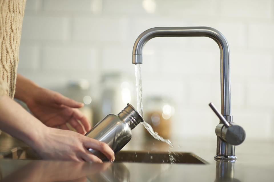 person washing water bottle at sink