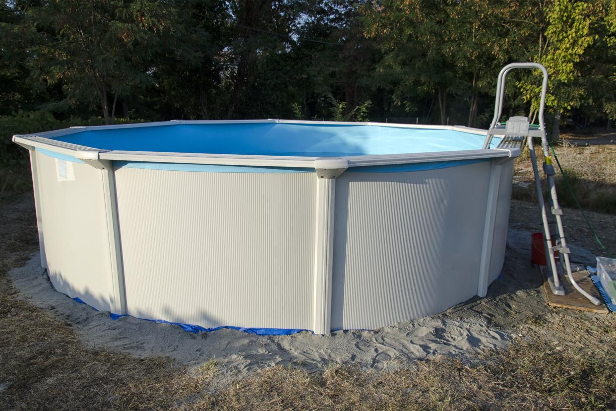 Metal steel frame above-ground pool with ladder on grass with trees in the background