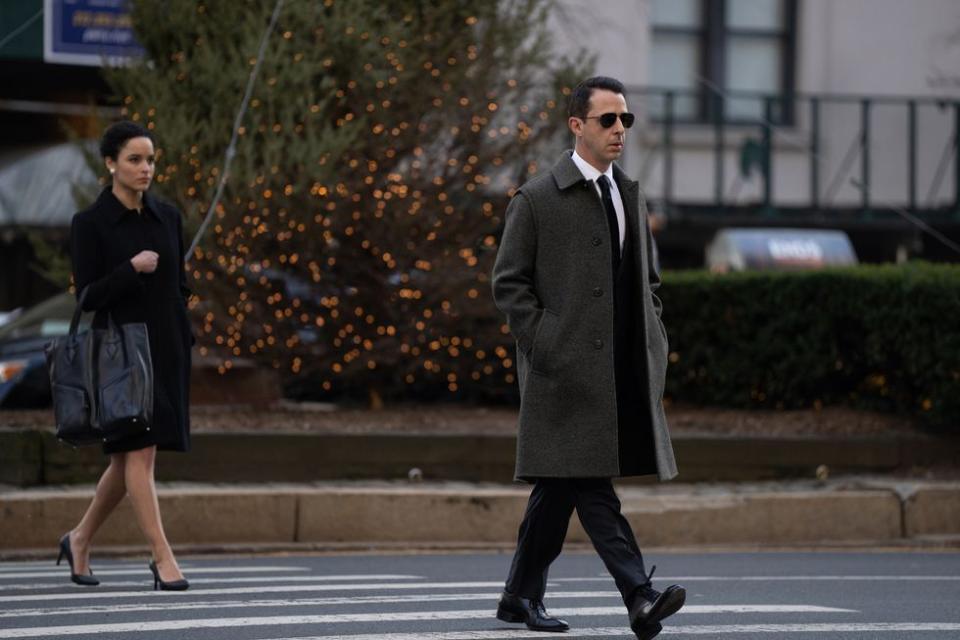a man and woman walking across a street