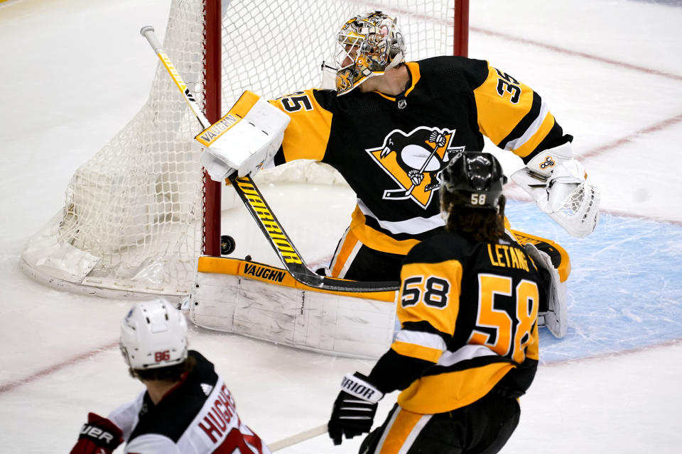 New Jersey Devils' Jack Hughes (86) scores against Pittsburgh Penguins goaltender Tristan Jarry (35) with Kris Letang (58) defending during the third period of an NHL hockey game in Pittsburgh, Tuesday, April 20, 2021. (AP Photo/Gene J. Puskar)