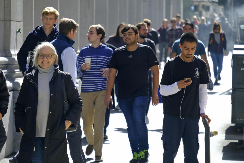 People make their way through the Financial District along Montgomery Street Friday, Oct. 18, 2019, in San Francisco. California's unemployment rate fell to a new record low of 4% in September. The state Employment Development Department says Friday that employers added 21,300 nonfarm payroll jobs, extending California's record job expansion to 115 months. (AP Photo/Eric Risberg)