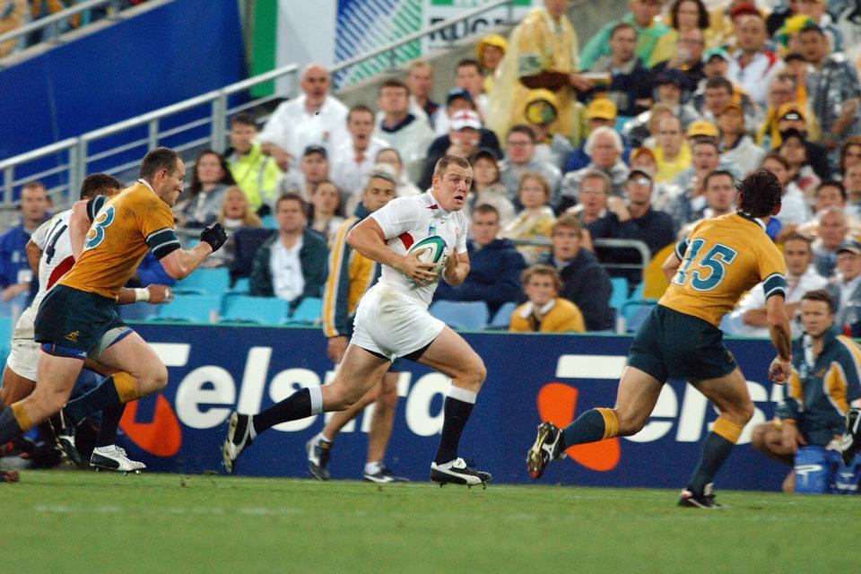 Mike Tindall (England) runs with the ball with Mat Rogers (15) covering across Telstra Stadium (now Stadium Australia) Sydney