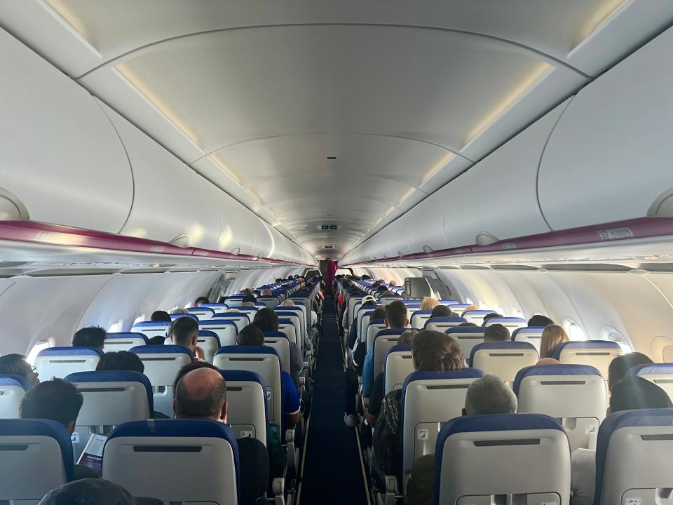 The cabin of a Wizz Air Airbus A320neo as viewed from the aisle looking forward