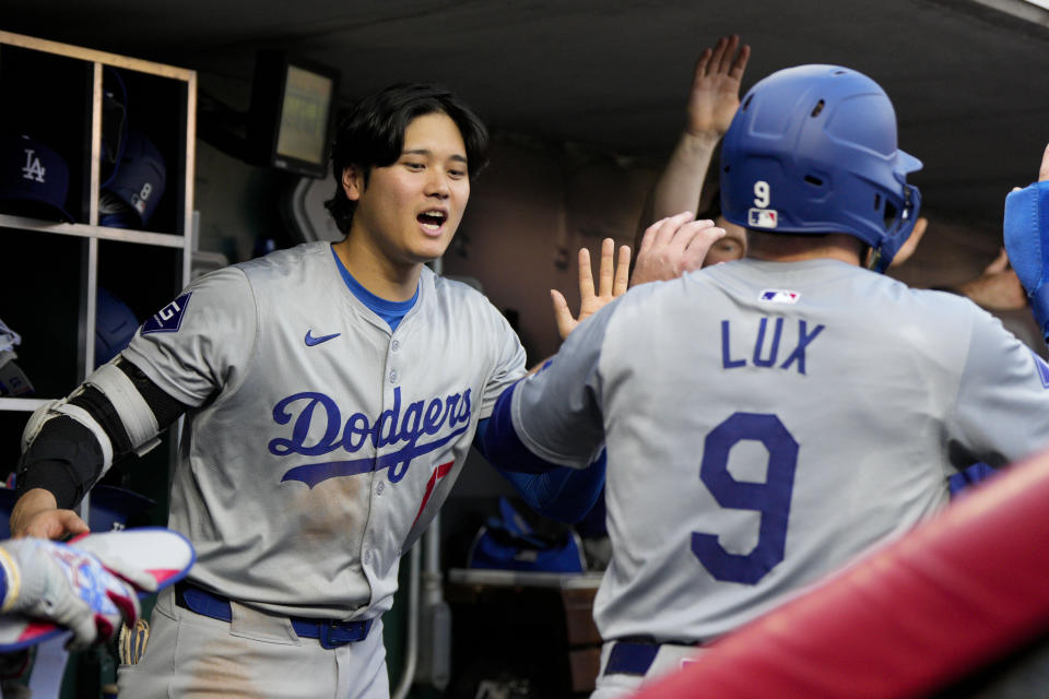 Los Angeles Dodgers' Gavin Lux (9) celebrates with Shohei Ohtani after scoring on a double by Chris Taylor against the Cincinnati Reds during the second inning of a baseball game Friday, May 24, 2024, in Cincinnati. (AP Photo/Jeff Dean)