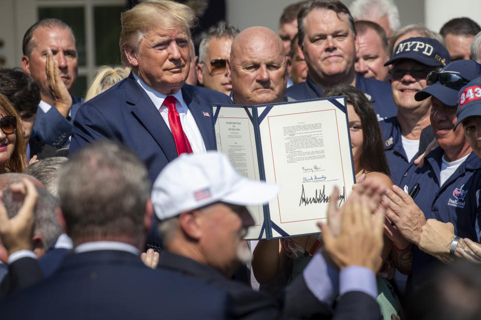 President Donald Trump is surrounded by first responders after signing H.R. 1327, an act ensuring that a victims' compensation fund related to the Sept. 11 attacks never runs out of money, in the Rose Garden of the White House, Monday, July 29, 2019, in Washington. (AP Photo/J. Scott Applewhite)