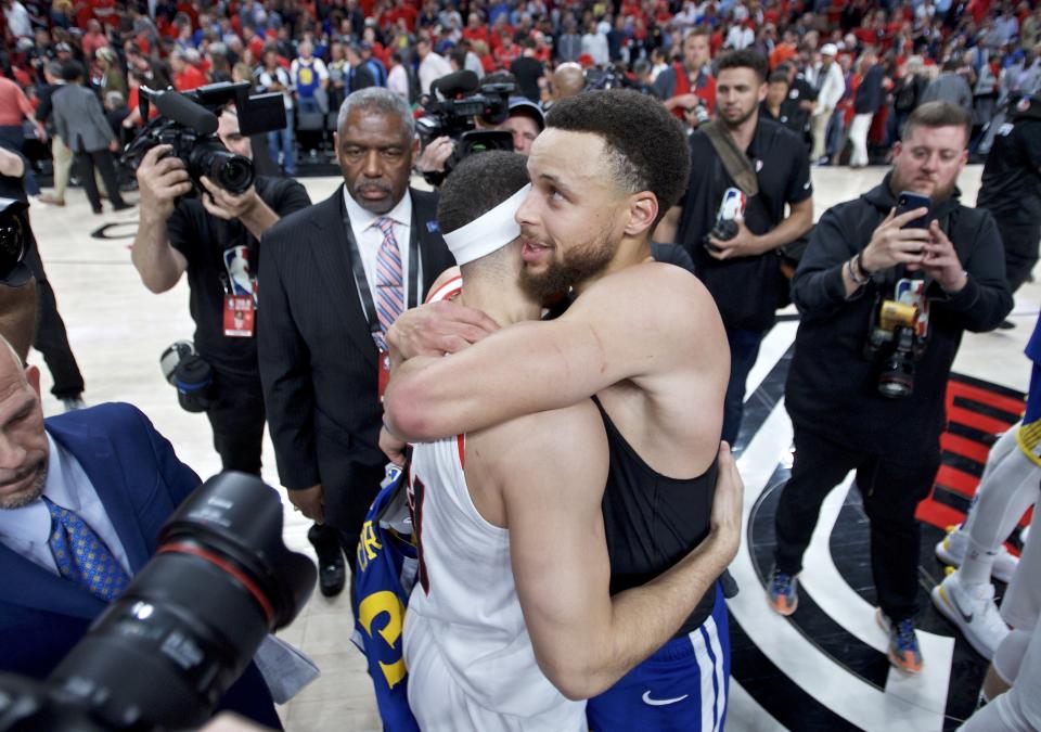 Golden State Warriors guard Stephen Curry, right, hugs his brother, Portland Trail Blazers guard Seth Curry at the end of Game 4 of the NBA basketball playoffs Western Conference finals Monday, May 20, 2019, in Portland, Ore. The Warriors won 119-117 in overtime. (AP Photo/Craig Mitchelldyer)