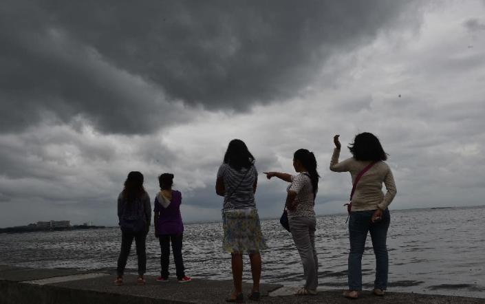 People watch as storm clouds gather around Manila Bay on October 16, 2016, after Typhoon Sarika passed north of the capital overnight (AFP Photo/Ted Aljibe)
