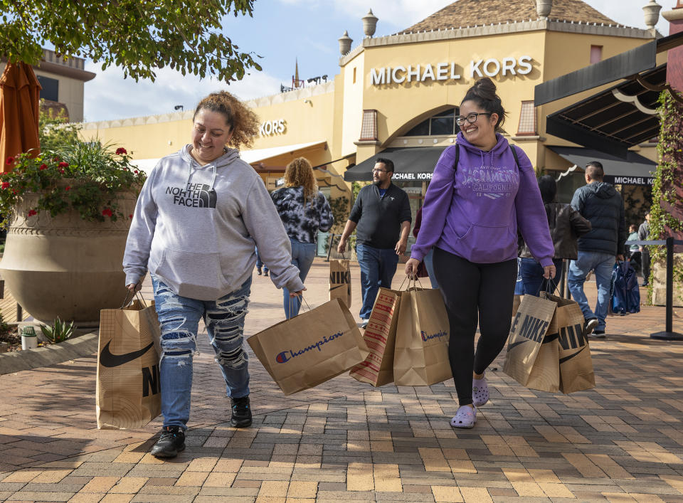 COMMERCE, CA-DECEMBER 23, 2023:Mia Maagallanes, left, of Wilmington, and her friend Jennifer Ramirez of San Pedro make their way with Christmas gifts after shopping for family members at the Citadel Outlets in Commerce.   (Mel Melcon / Los Angeles Times via Getty Images)