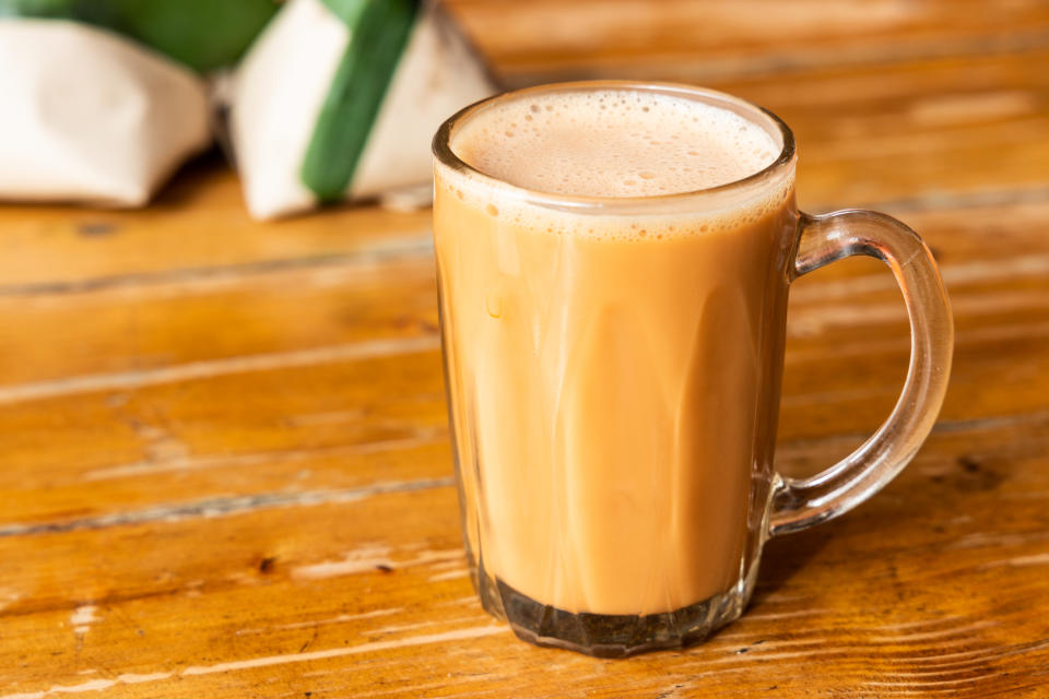 Teh tarik with nasi lemak pack in banana leaf in background