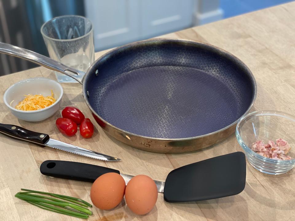 ingredients for a fried egg omelet sitting around a frying pan on a counter