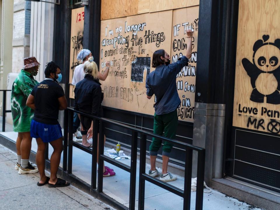 Street artists are seen working on boarded up buildings amid coronavirus closures and anti-racism protests in SoHo on June 16, 2020 in New York City.