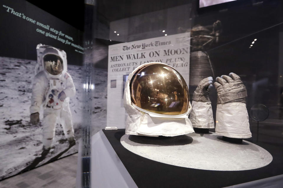 FILE - In this April 11, 2019 file photo, Buzz Aldrin's outer visor and gloves worn while walking on the moon are displayed near a photo of Aldrin at Destination Moon: The Apollo 11 Mission exhibit at the Museum of Flight in Seattle. The exhibit celebrates the 50th anniversary of the U.S. manned moon landing on July 20, 1969. (AP Photo/Elaine Thompson)