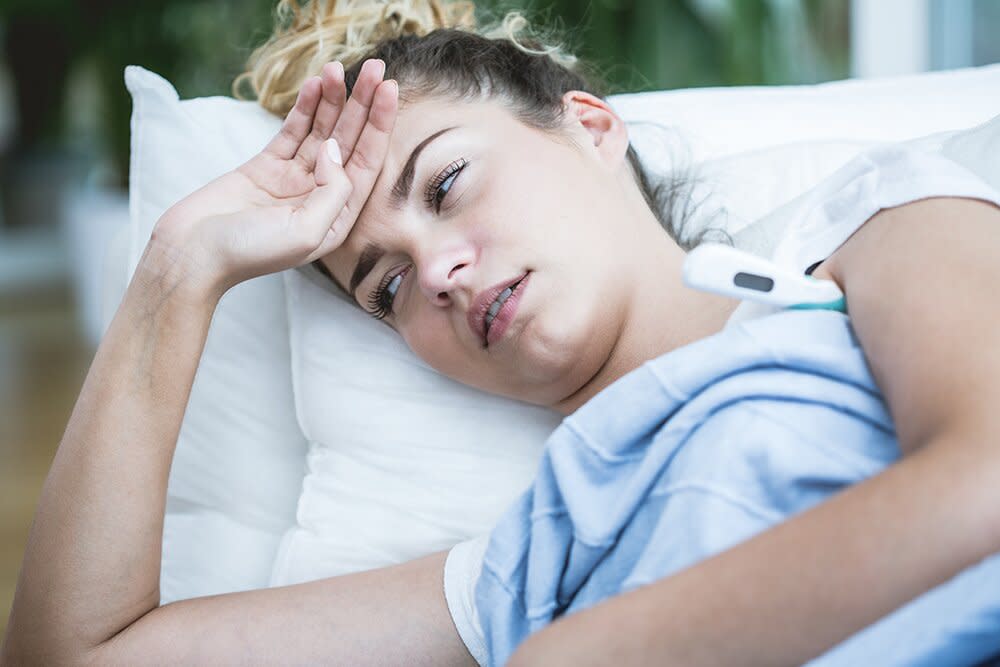 sick woman laying down with hand on forehead