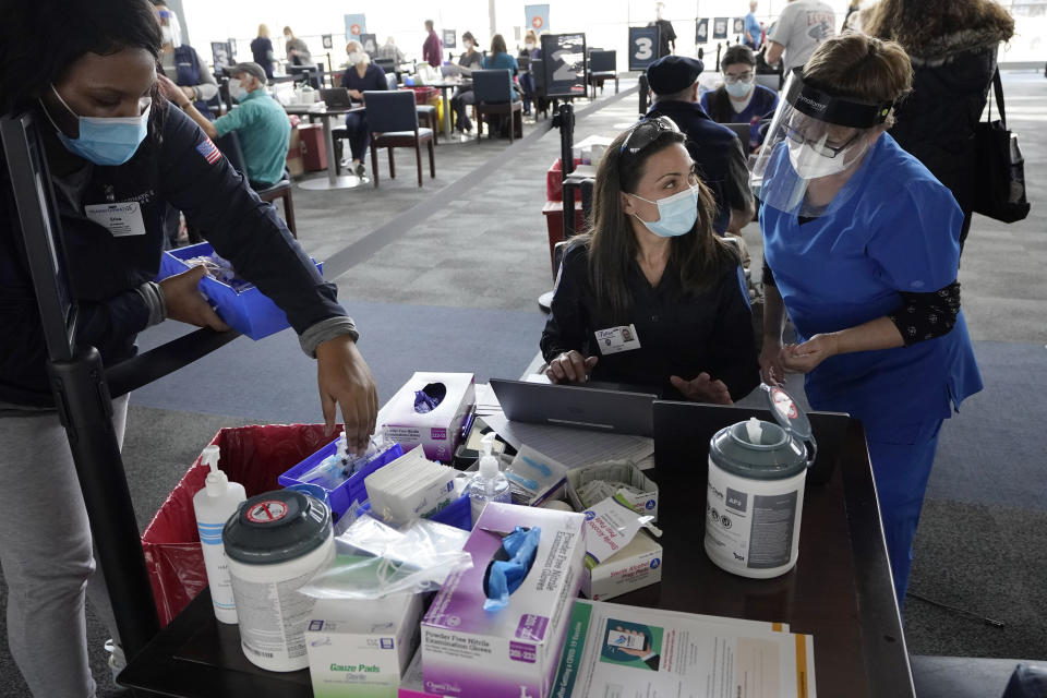 Emergency medical technician Alyssa Mucci, center, speaks with RN Mary McGovern, right, as they prepare to give COVID-19 vaccinations, Thursday, Feb. 11, 2021, at a vaccination center at Gillette Stadium in Foxborough, Mass. (AP Photo/Steven Senne)