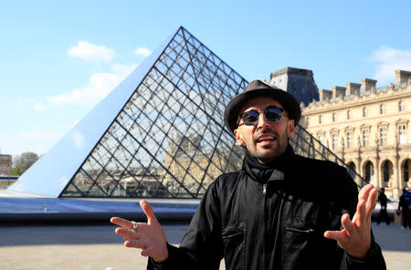 French artist JR talks during an interviews as he works in the courtyard of the Louvre Museum near the glass pyramid designed by Ieoh Ming Pei as the Louvre Museum celebrates the 30th anniversary of its glass pyramid in Paris, France, March 26, 2019. REUTERS/GonzaloÊFuentes