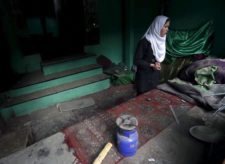 An Afghan girl looks out as she stands inside of a damaged shrine after a suicide attack in Kabul March 25, 2015. REUTERS/Mohammad Ismail