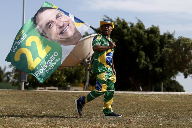 Un simpatizante del presidente brasileño y candidato a la reelección por el Partido Liberal, Jair Bolsonaro, camina por una calle con una bandera, en Brasilia, Brasil, el 13 de octubre de 2022