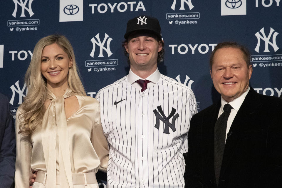 New York Yankees' Gerrit Cole, center, joined by his wife Amy, left, and agent Scott Boras, is introduced as the baseball club's newest player during a media availability, Wednesday, Dec. 18, 2019 in New York. The pitcher agreed to a 9-year, $324 million contract. (AP Photo/Mark Lennihan)