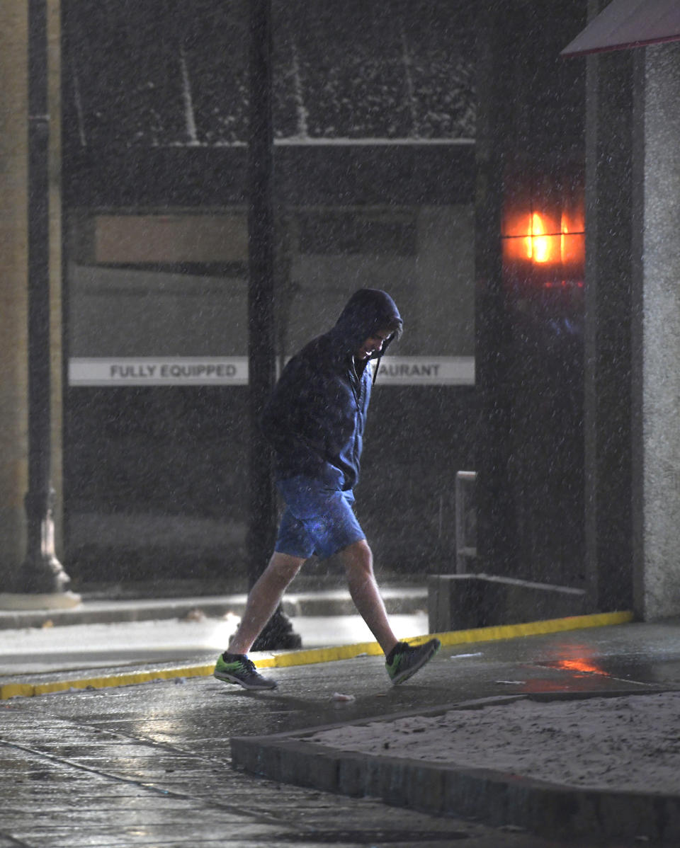 In this Sunday, Dec. 1, 2019 photo, a man heads into a CVS Pharmacy on Front Street as it snows in Worcester, Mass. A wintry storm that made Thanksgiving travel miserable across much of the country gripped the East with a messy mixture of rain, snow, sleet and wind. (Christine Peterson/Worcester Telegram & Gazette via AP)