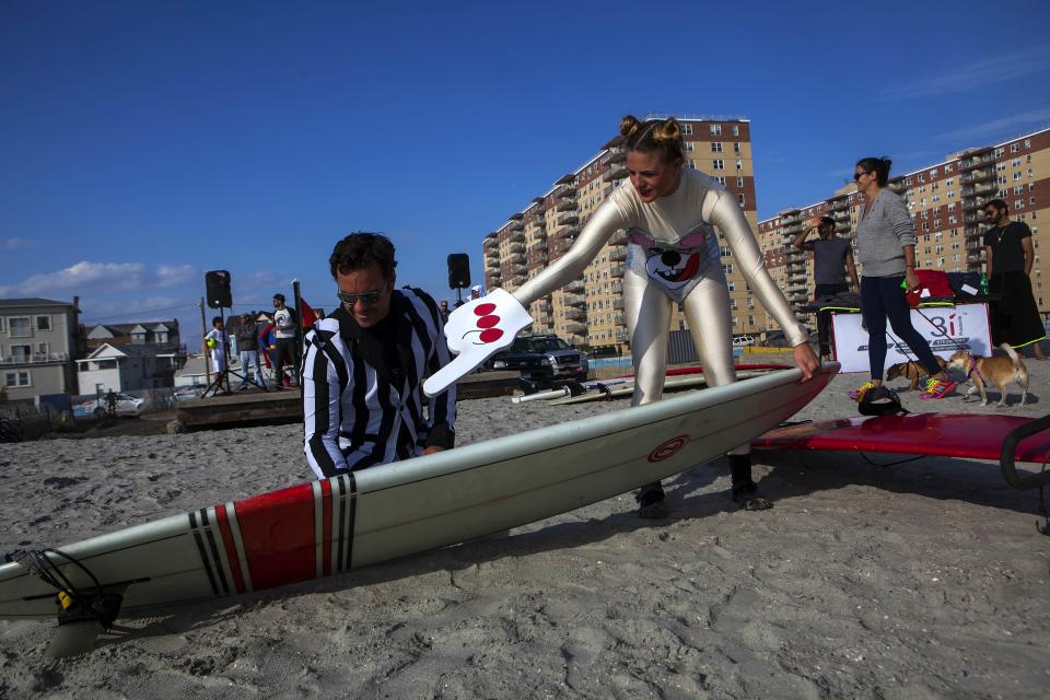 Participants in costume wax a board before the third annual Rockaway Halloween surf competition at Rockaway Beach in the Queens borough of New York