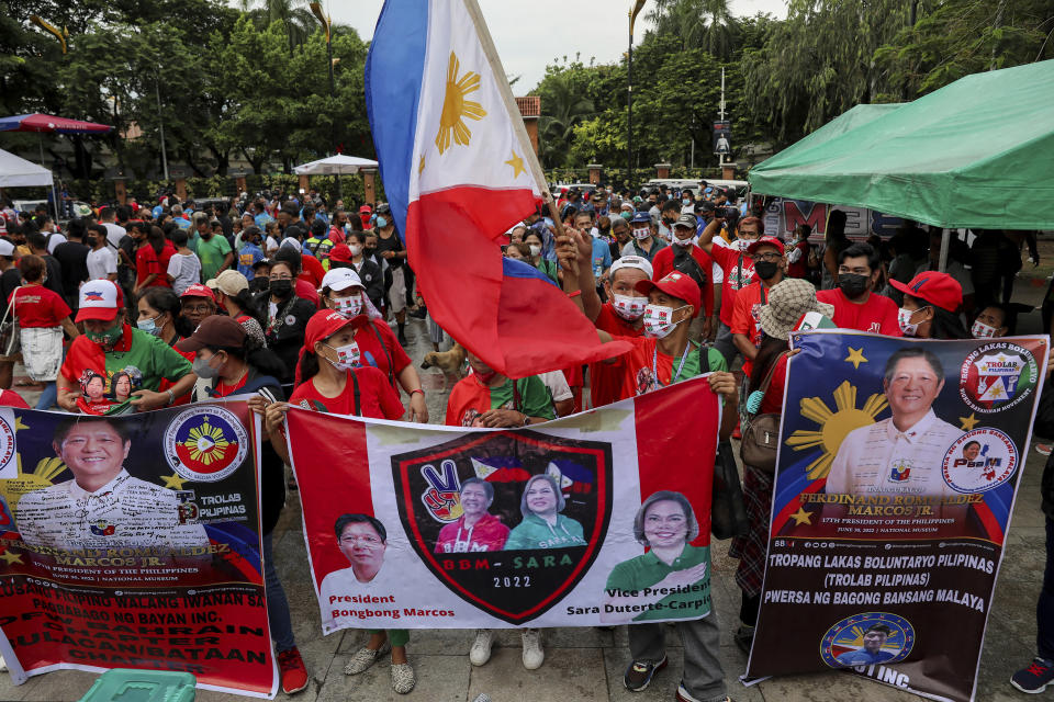 Suppoerters of President-elect Ferdinand Marcos Jr. carry signs and wave flags as they gather for his inauguration ceremony in Manila, Philippines on Thursday, June 30, 2022. Ferdinand Marcos Jr., the namesake son of an ousted dictator, was sworn in as Philippine president Thursday in one of history's greatest political comebacks but which opponents say was pulled off by whitewashing his family's image. (AP Photo/Basilio Sepe)