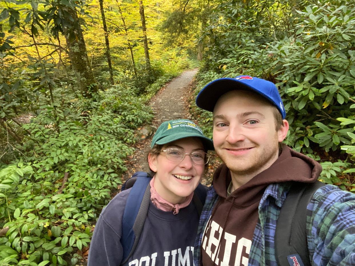 woman, reporter Kelsey Neubauer, and man take a selfie in the forest