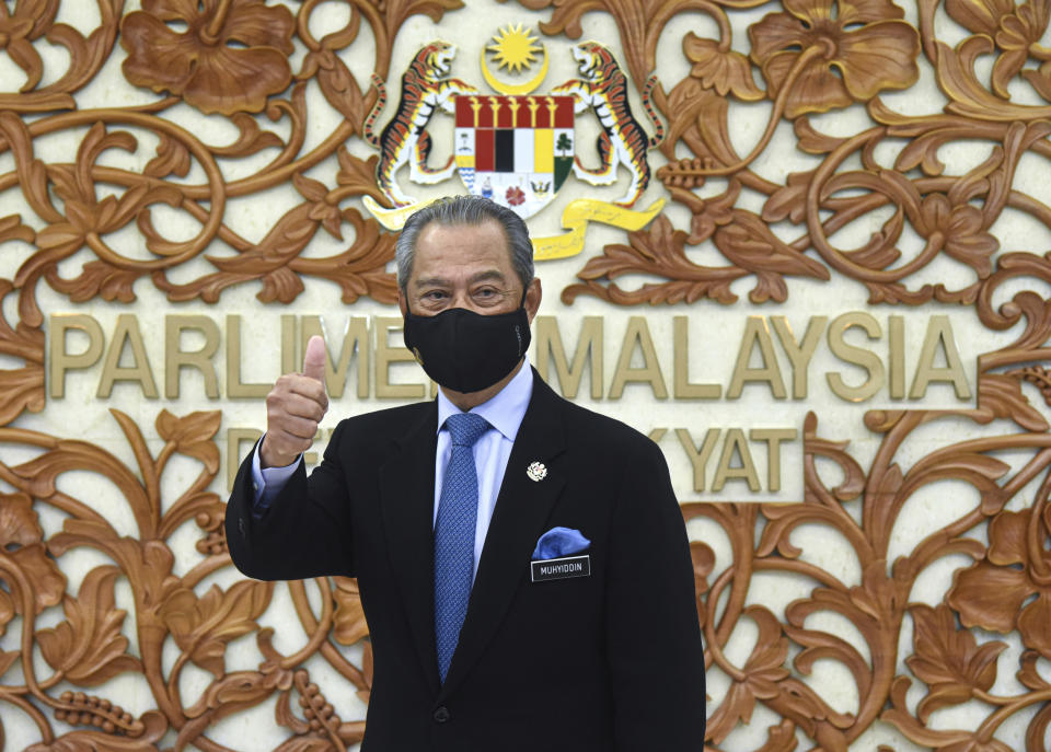In this photo released by Malaysia's Information Ministry, Prime Minister Muhyiddin Yassin poses for a picture at the parliament, in Kuala Lumpurf, Malaysia Thursday, Nov. 26, 2020. Malaysia's Parliament Thursday approved the government's proposed 2021 budget, throwing a political lifeline to embattled Prime Minister Muhyiddin Yassin amid strong resistance to his nine-month-old leadership. (Zarith Zulkifli/Malaysia's Department of Information via AP)