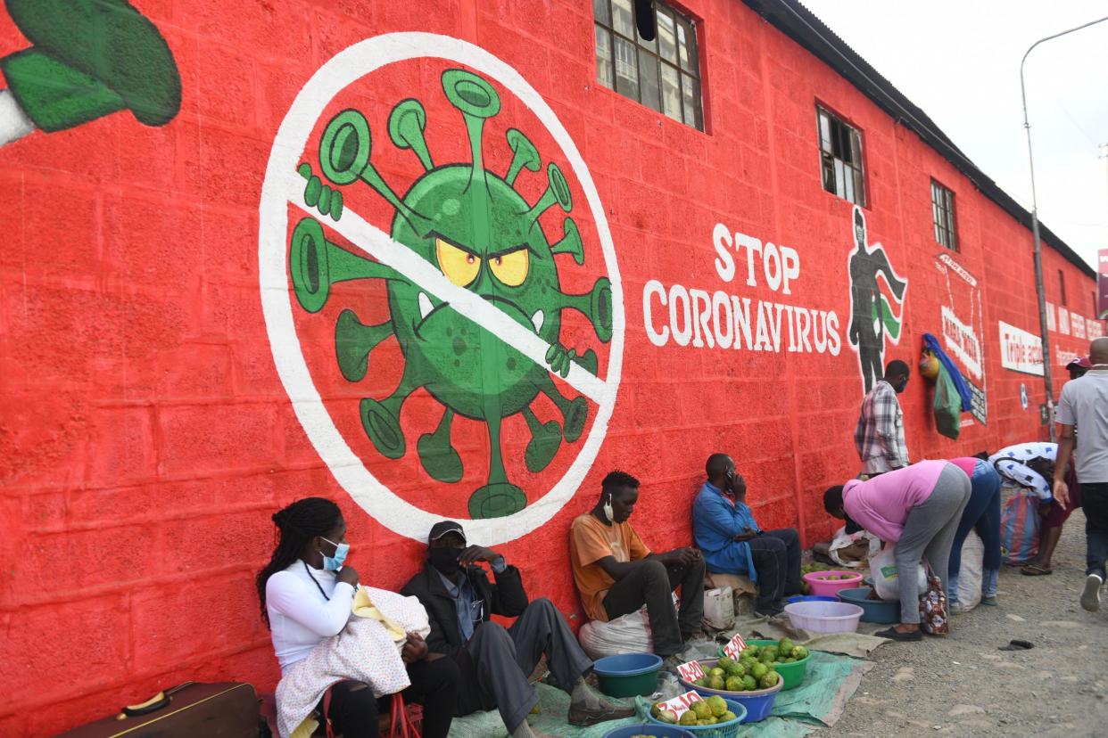 Traders sell their wares below graffiti raising awareness about Covid-19 in Nairobi last month: AFP via Getty Images