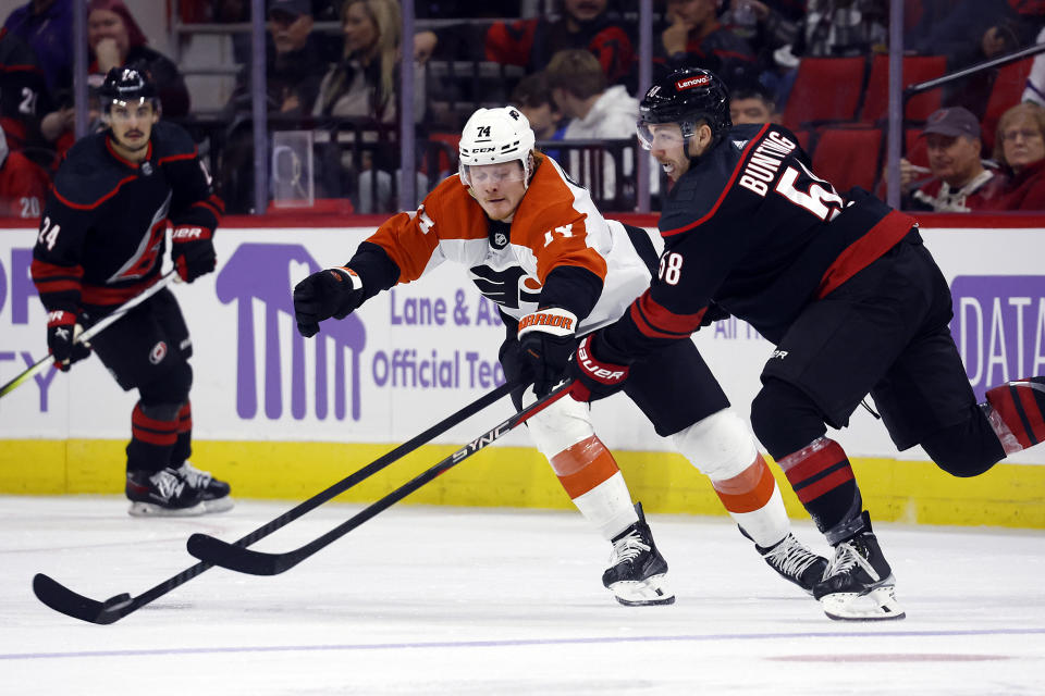 Carolina Hurricanes' Michael Bunting (58) clears the puck past Philadelphia Flyers' Owen Tippett (74) during the third period of an NHL hockey game in Raleigh, N.C., Wednesday, Nov. 15, 2023. (AP Photo/Karl B DeBlaker)