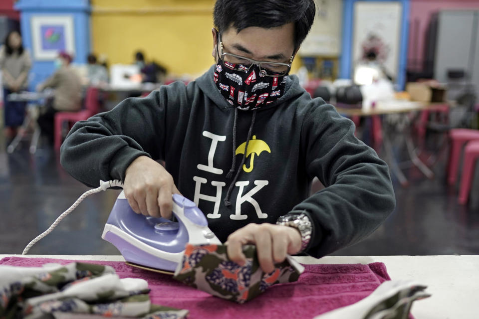 In this Monday, Feb. 17, 2020, photo, a volunteer irons a handmade cotton mask in Hong Kong. Volunteers from a Hong Kong theater group are turning their backstage skills to helping out against the new coronavirus, sewing reusable protective masks for those who can't access or afford them. Jo Ngai, a drama lover and founder of the Nonsensemakers, along with her friend Jessie Han, have turned a theater rehearsal room into a temporary handmade mask factory. (AP Photo/Kin Cheung)