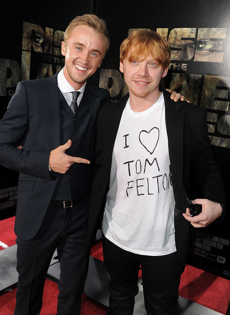 Tom posing with Rupert Grint, whose wearing an 'I heart Tom Felton shirt underneath a blazer' on the red carpet