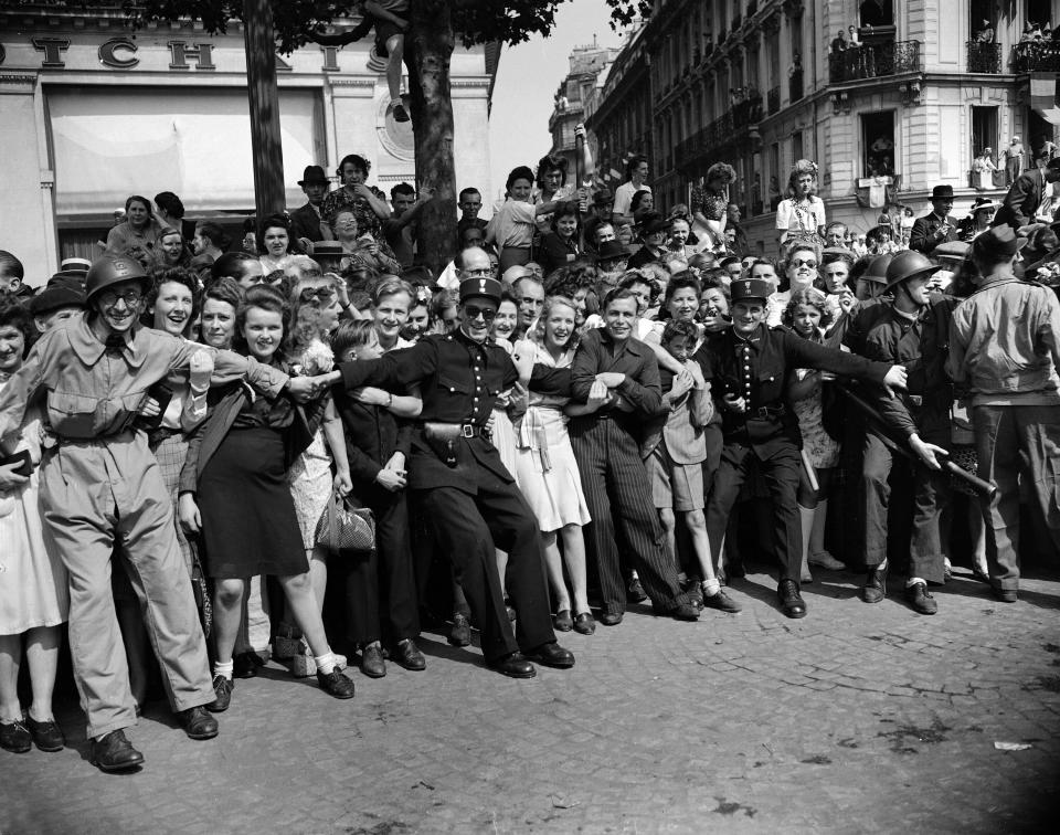 FILE - In this Aug. 26, 1944 file photo, gendarmes and F.F.I. hold back crowds of people as they throng the streets to see General Charles De Gaulle in Paris. The fighting for the liberation of Paris took place from August 19 to August 25, 1944. (AP Photo/Laurence Harris, File)