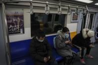 Commuters wearing face masks to help curb the spread of the coronavirus ride on a subway train near an advertisement carrying the words "Come on 2021, It will work" in Beijing, Tuesday, Jan. 26, 2021. Countries must cooperate more closely in fighting the challenges of the pandemic and climate change and in supporting a sustainable global economic recovery, Chinese President Xi Jinping said on Monday in an address to the World Economic Forum. (AP Photo/Andy Wong)