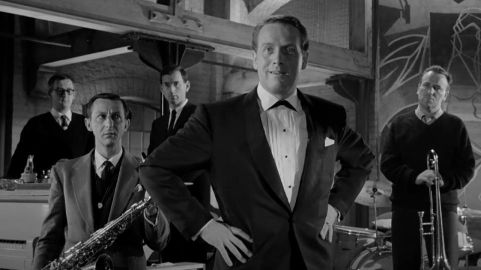 Patrick McGoohan standing in front of a band in All Night Long.