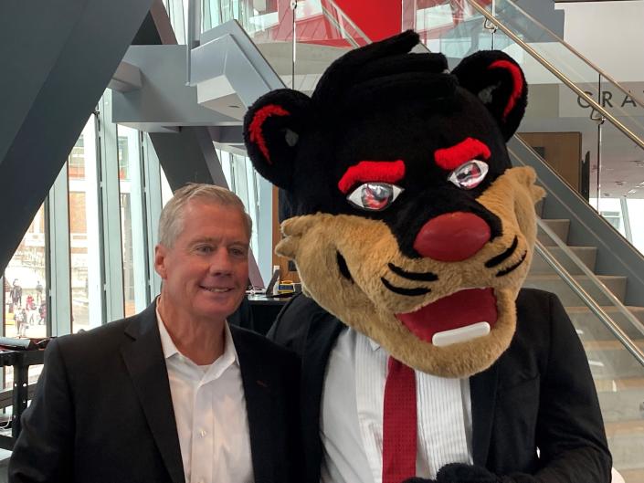 TQL President Kerry Byrne smiles with the Bearcat mascot Tuesday. The freight brokerage firm has entered into a long-term sports partnership with the University of Cincinnati.