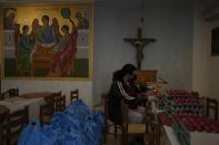 A volunteer sits next to bags containing food, which will be deliver to low income families, as he packs colored eggs for Easter at an Orthodox Church in Athens, Greece, on Tuesday, April 19, 2022. For the first time in three years, Greeks were able to celebrate Easter without the restrictions made necessary by the coronavirus pandemic. (AP Photo/Thanassis Stavrakis)