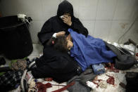 A Palestinian woman cries as she sits next to her girl wounded in the Israeli bombardment of the Gaza Strip while receiving treatment at the Nasser hospital in Khan Younis, Southern Gaza Strip, Monday, Jan. 22, 2024. (AP Photo/Mohammed Dahman)