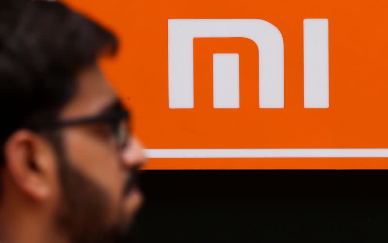 A man walks past a logo of Xiaomi, a Chinese manufacturer of consumer electronics, outside a shop in Mumbai