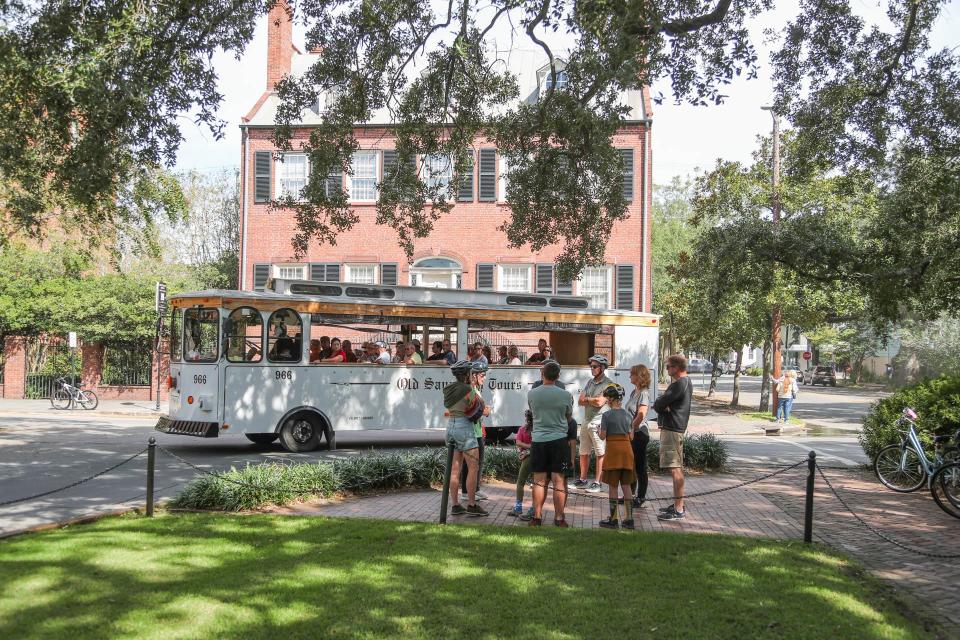An Old Savannah Tours Trolley passes a bicycle tour in Columbia Square on Tuesday, October 10, 2023.