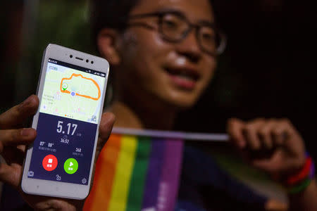 A participant poses with his smartphone showing the distance of 5.17 km he covered during a run to mark International Day Against Homophobia in a park in Beijing, China, May 17, 2018. REUTERS/Thomas Peter