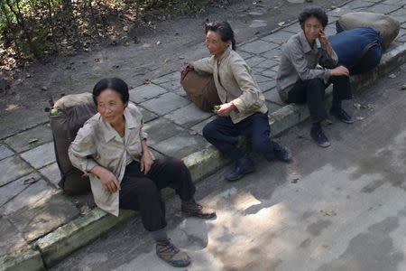 Street vendors sit on a sidewalk in Samjiyon County, Ryanggang Province, North Korea in this picture taken September 6, 2010. REUTERS/Roman Harak/Handout via Reuters