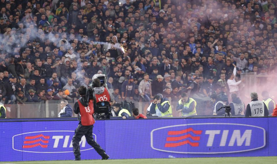 Napoli fans throw flares prior to the start of Italian Cup final match between Fiorentina and Napoli in Rome's Olympic stadium Saturday, May 3, 2014. At least one fan and one police officer were reportedly shot before the Italian Cup final between Napoli and Fiorentina, and the fan was in serious condition. As a result, the start of the final was delayed, and there were scenes of violence inside the stadium with a firefighter injured by fireworks thrown from the stands. The shootings occurred in an area where Napoli fans were gathering for the match, the ANSA news agency reported. (AP Photo/Gregorio Borgia)