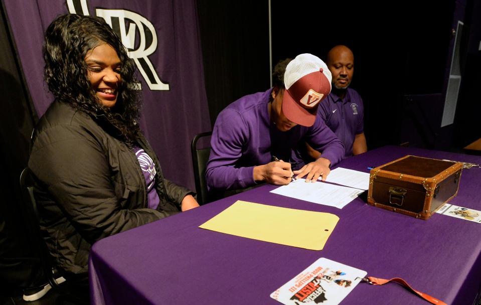 Cane Ridge standout Mose Phillips III signs his letter of intent to play football at Virginia Tech University as his parents Brandi and Mose Phillips Jr. watch during a signing day ceremony at Cane Ridge High School on Wednesday, Dec. 21, 2022, in Antioch, Tenn. 