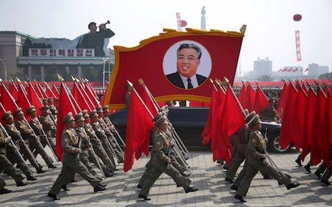 North Korean soldiers carry flags and a photo of late leader Kim Il Sung during a military parade  - Credit: AP Photo/Wong Maye-E