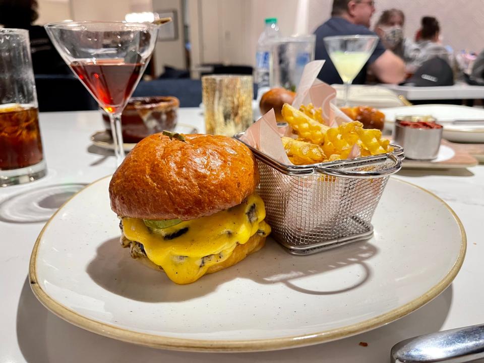 burger on a plate next to a basket of french fries at disney world steakhouse 71 restaurant