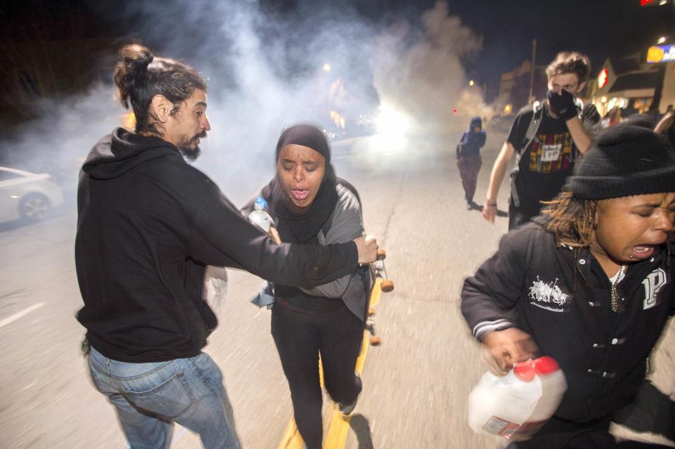 Protesters retreat while police officers deploy teargas to disperse a crowd comprised largely of student protesters during a protest against police violence in the U.S., in Berkeley