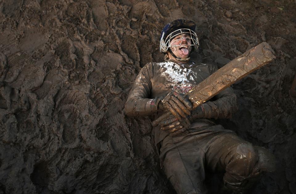 A competitor dressed as a cricketer lies in the mud during the Tough Guy event in Perton