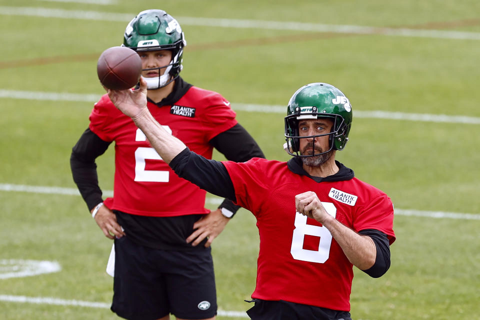 Aaron Rodgers loosens up as Zach Wilson looks on. (Rich Schultz/Getty Images)