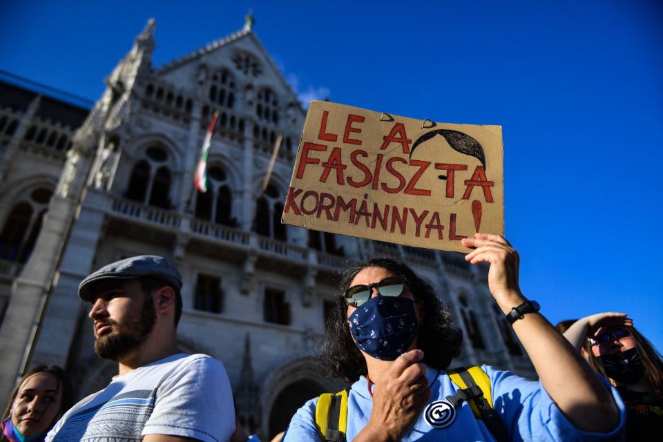 A participant holds a placard reading 'Down with the Fascist government' in front of the parliament building in Budapest, Hungary, June 14, 2021, during a demonstration against the Hungarian government's bill seeking to ban the 